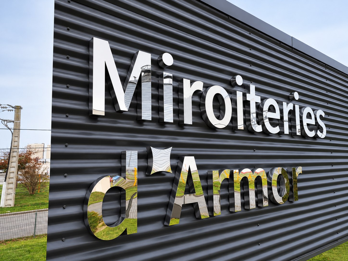 Lettres Miroiteries d’Armor en inox à finition miroir sur un bardage gris