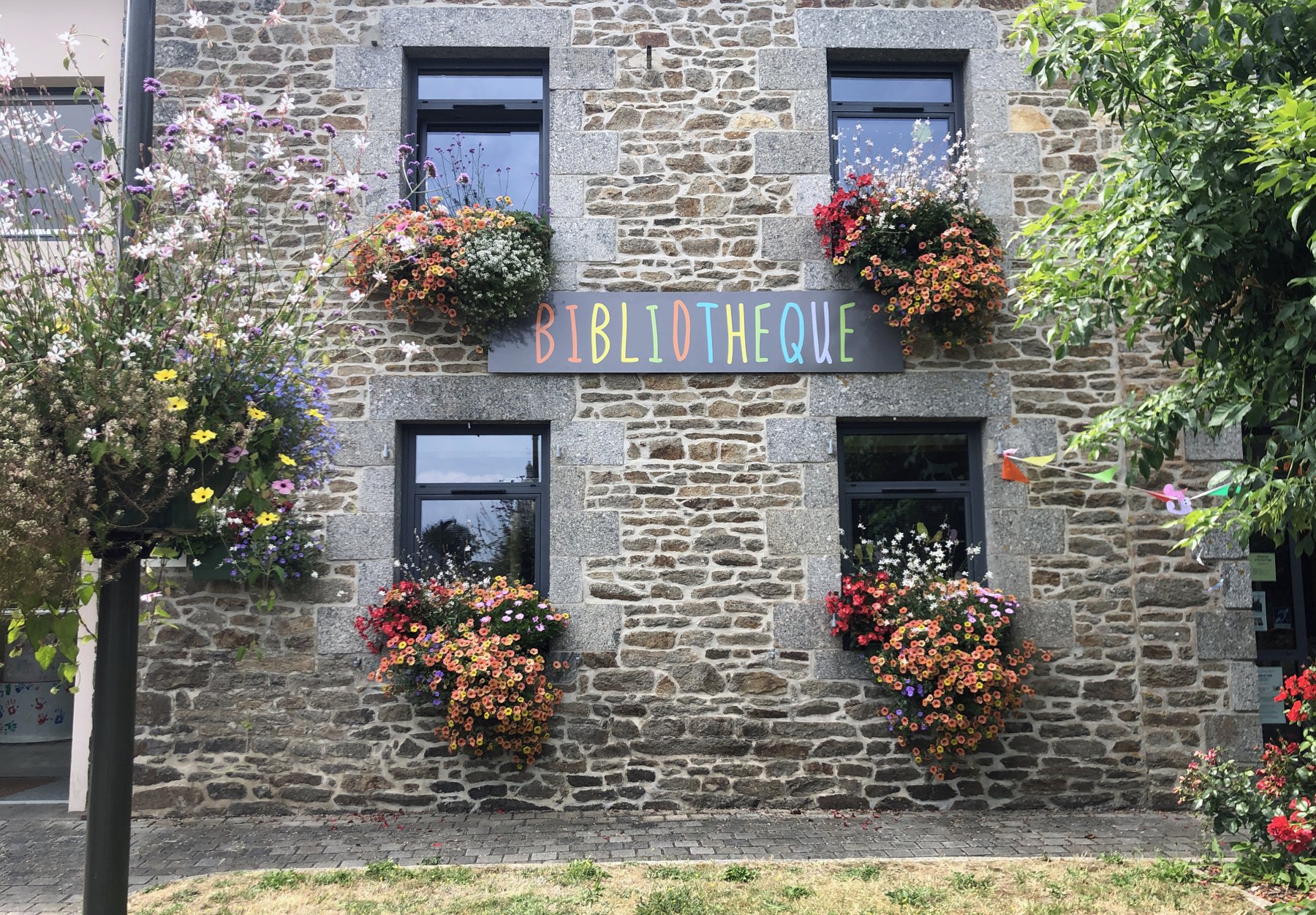 Lettres Bibliothèque sur la façade en pierre d’un bâtiment communal.