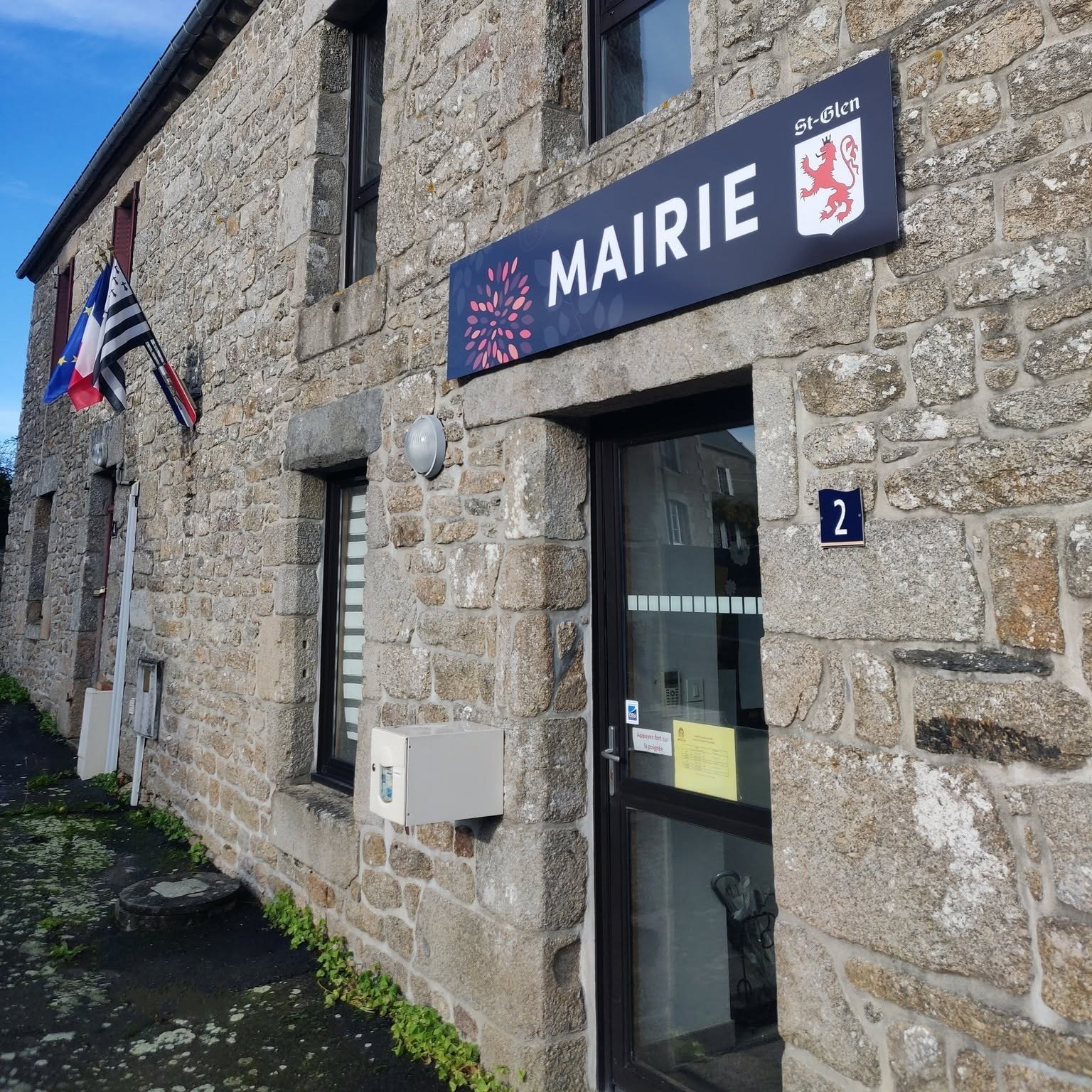 Enseigne Mairie et blason au-dessus d’une entrée dans un bâtiment en pierre.