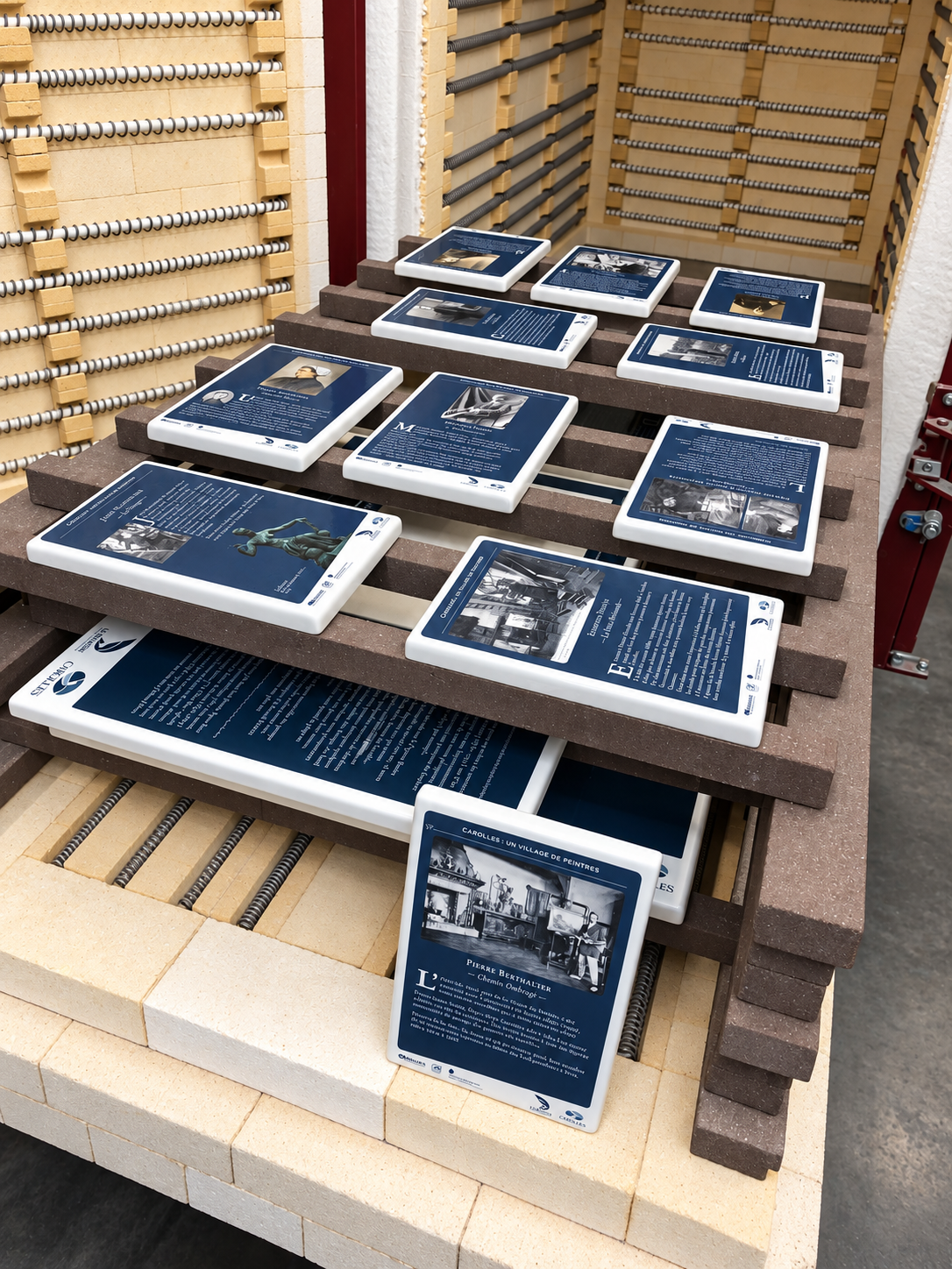 Plaques illustrées disposées sur le plateau d’un four d’émaillage.