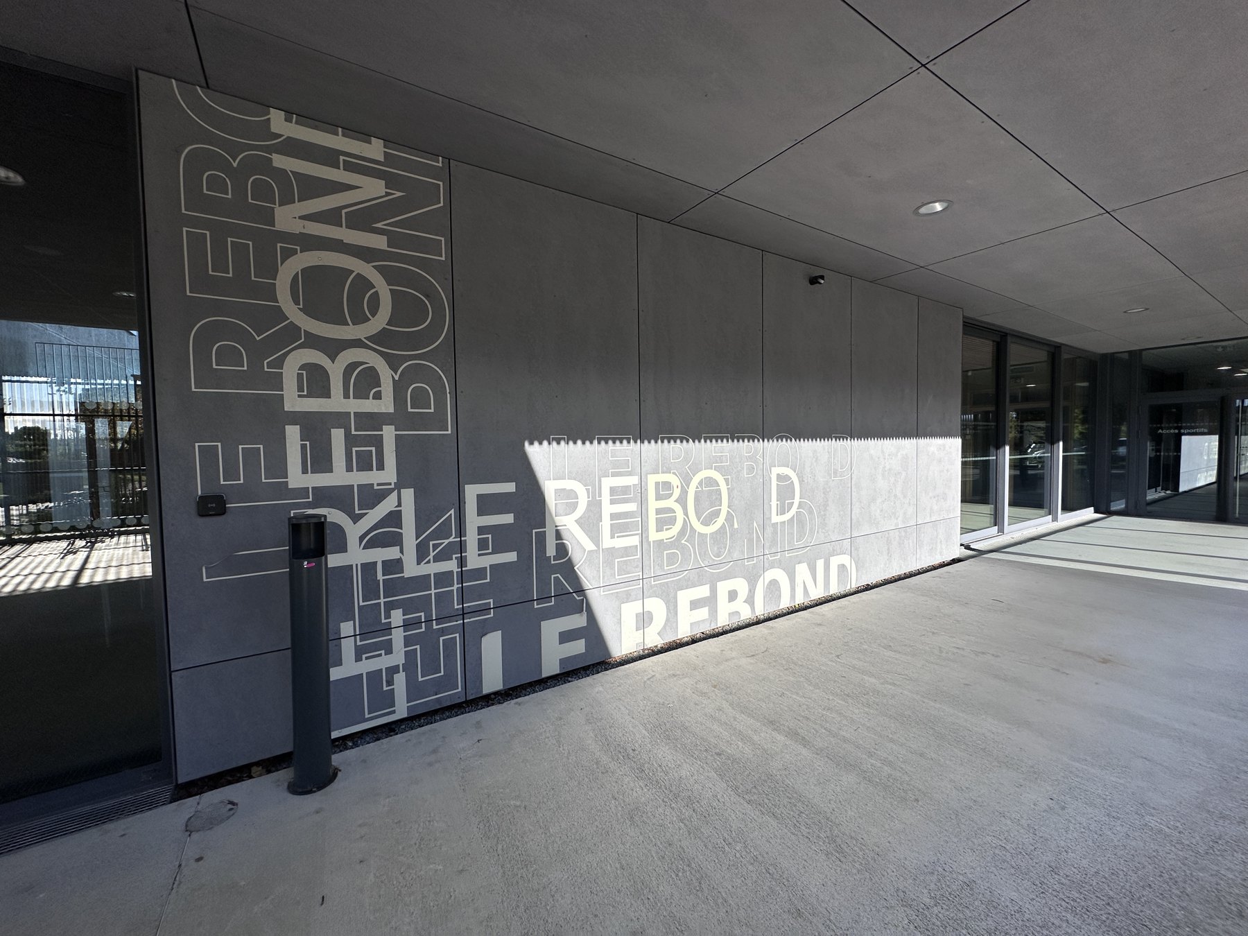 Habillage graphique typographique sur la façade vitrée d’un équipement public.