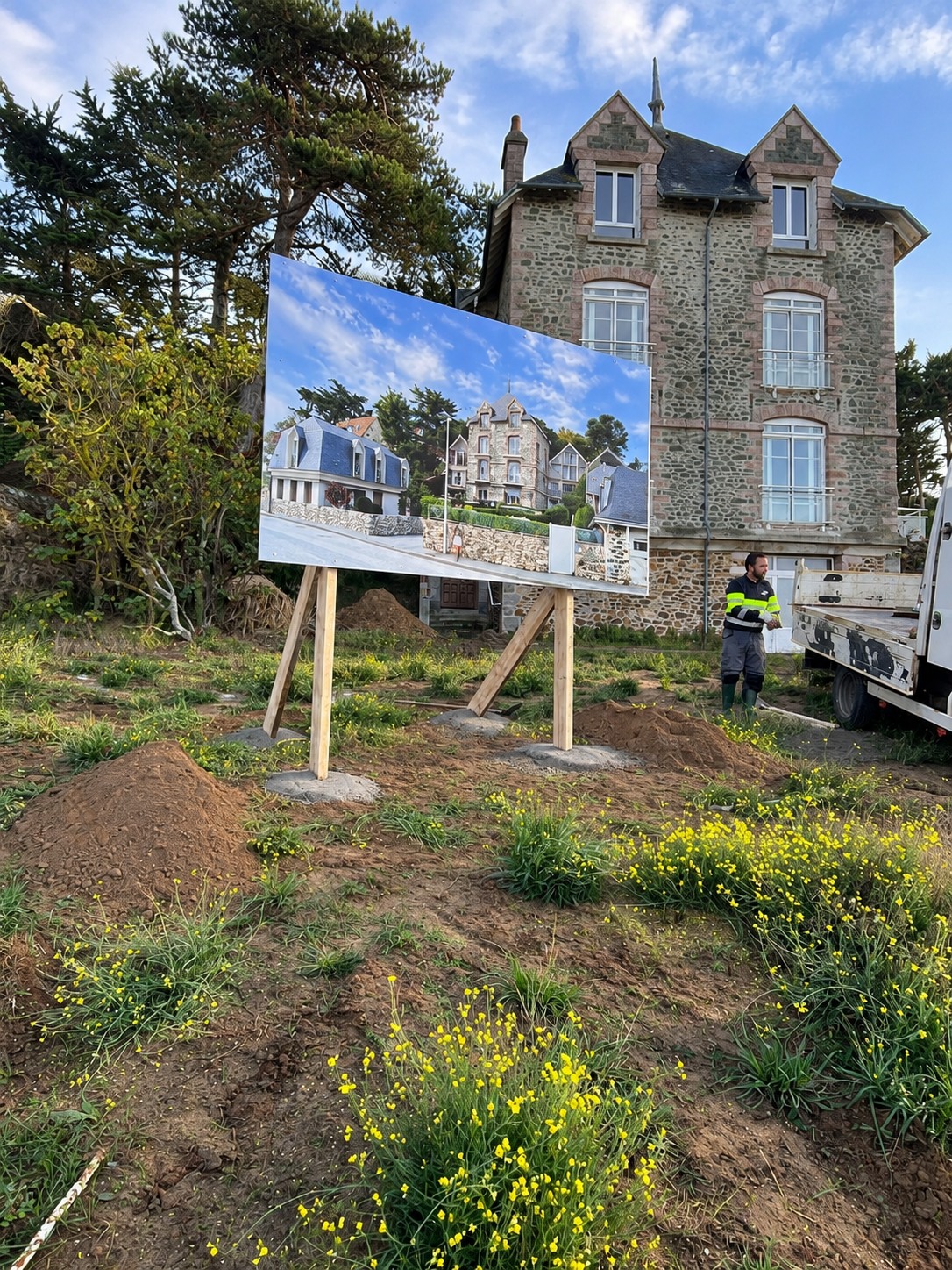 Panneau de présentation d’un projet immobilier installé sur des pieds en bois.