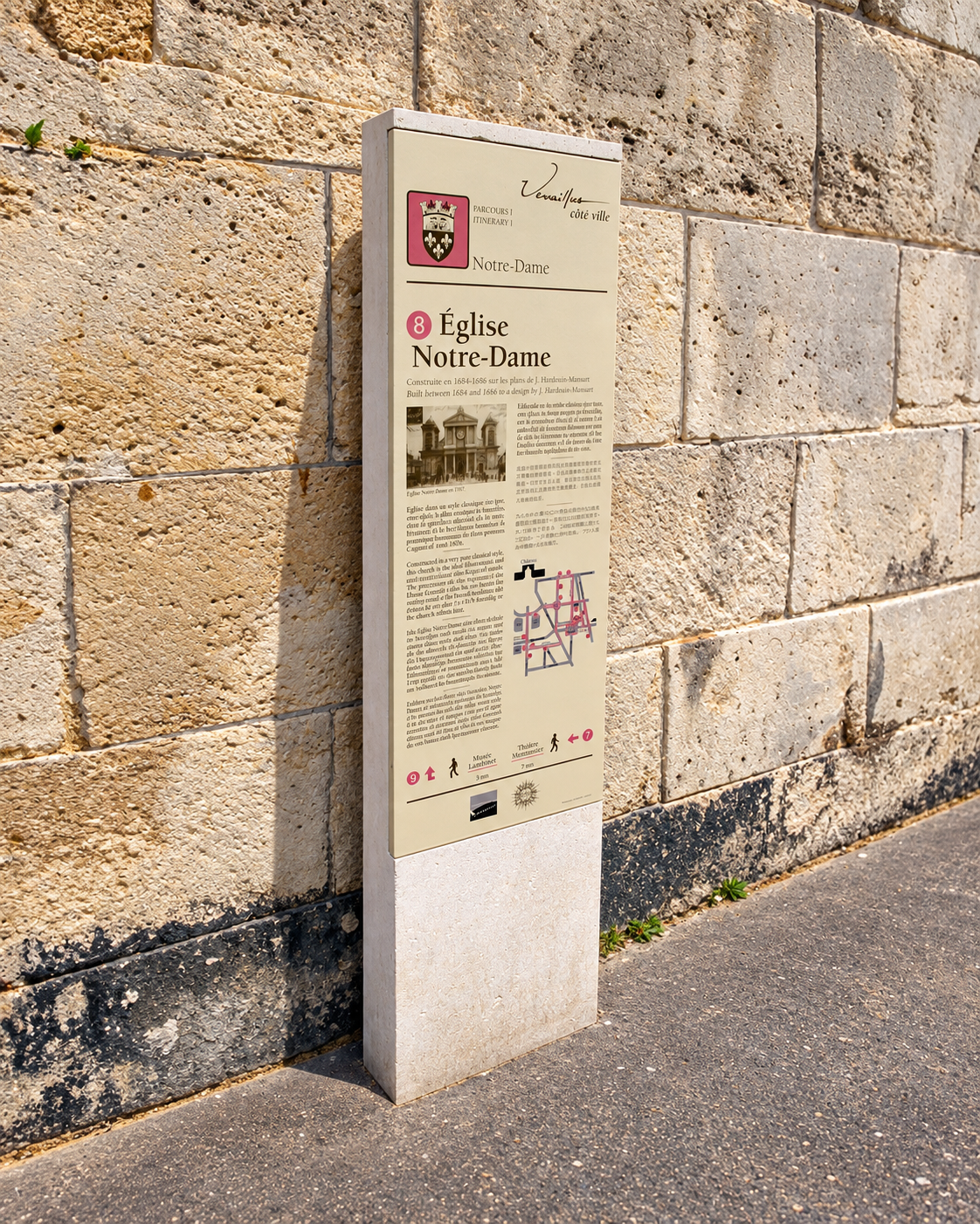 Plaque du parcours d’interprétation de la ville de Versailles fixée sur un mur en pierre.