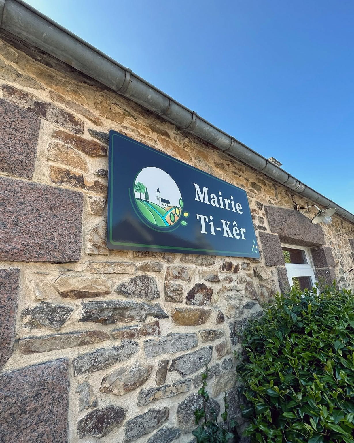 Plaque Mairie Ti-Kêr avec logo de Coatascorn sur une façade en pierre.