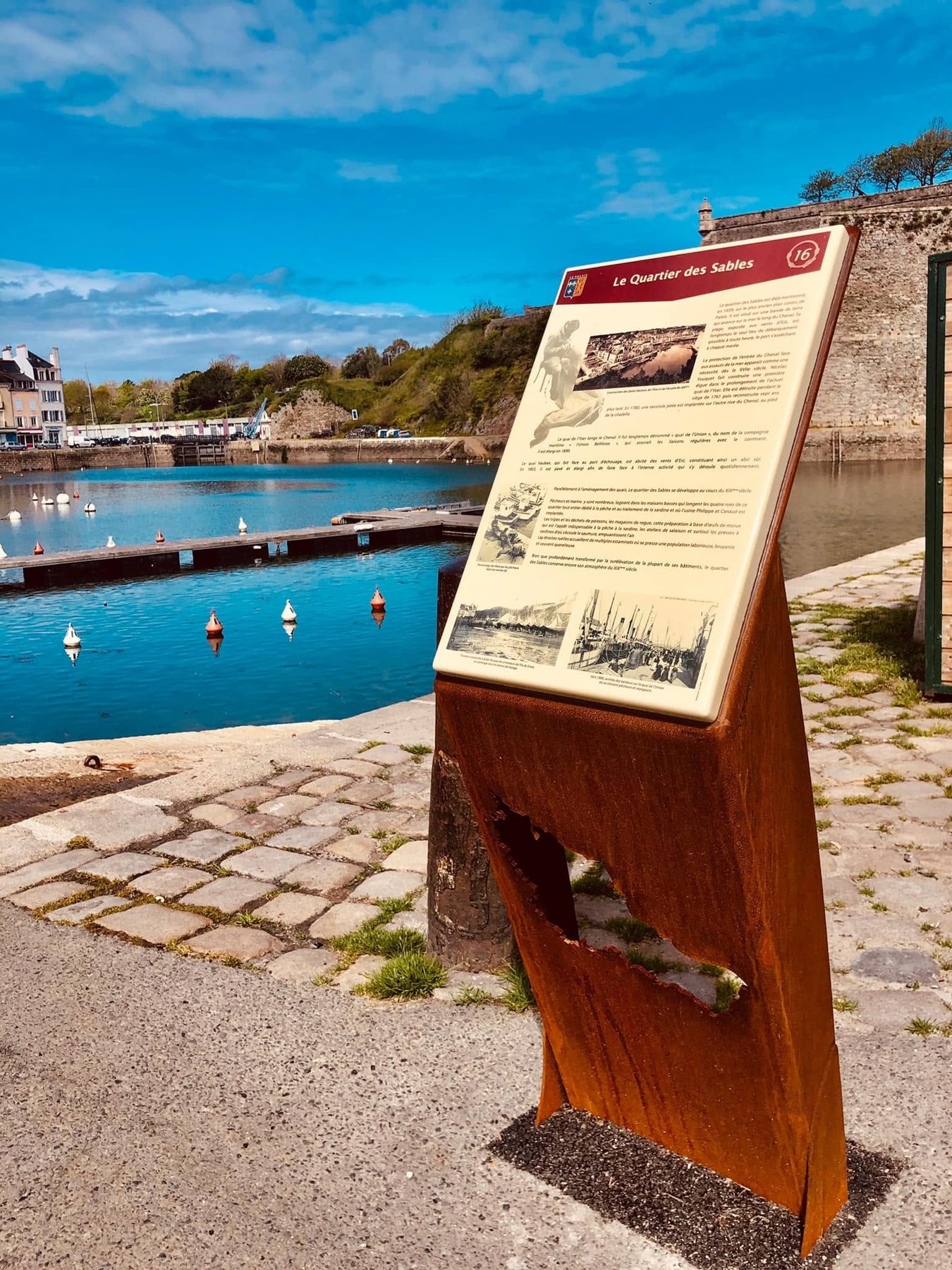 Pupitre d’interprétation au bord d’un port, avec photographie d’archives et texte explicatif.