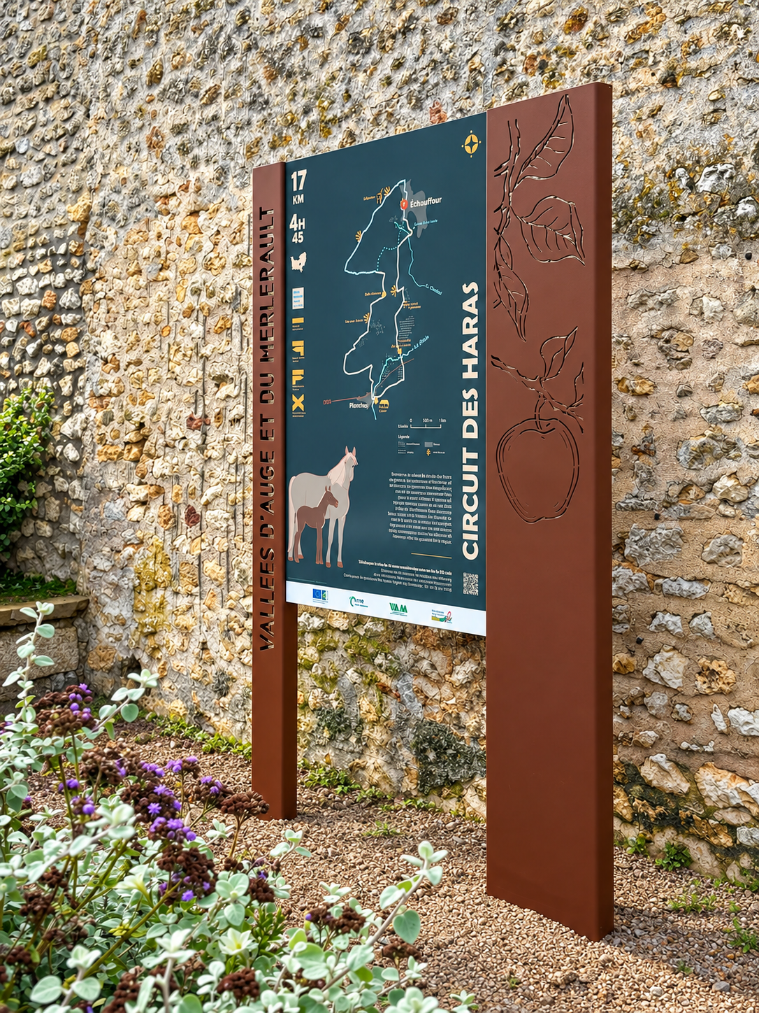Totem du Circuit des Haras installé contre un mur en pierre.