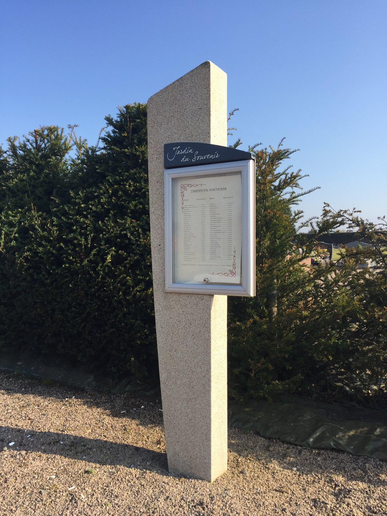 Vitrine d’information fixée sur une borne dans un cimetière.